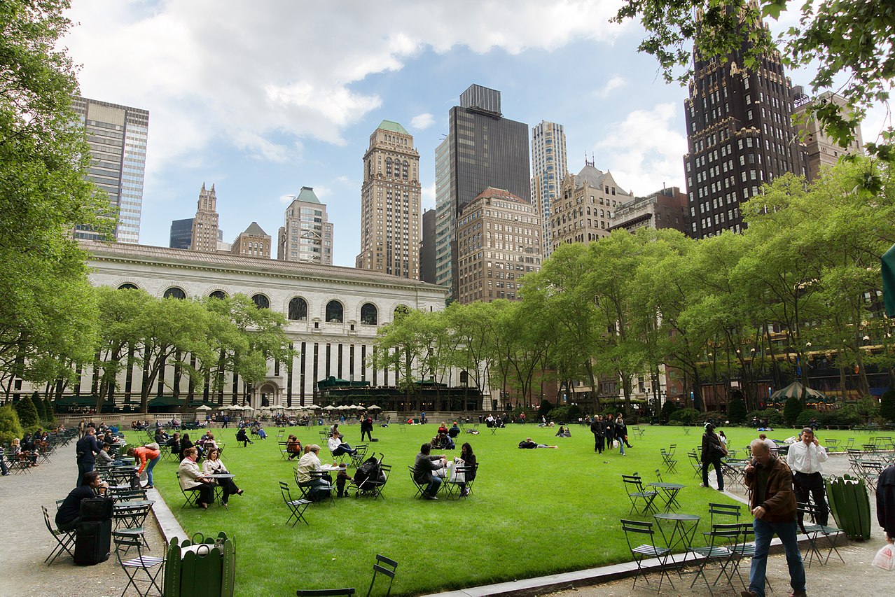 An urban park with a big lawn, full of people